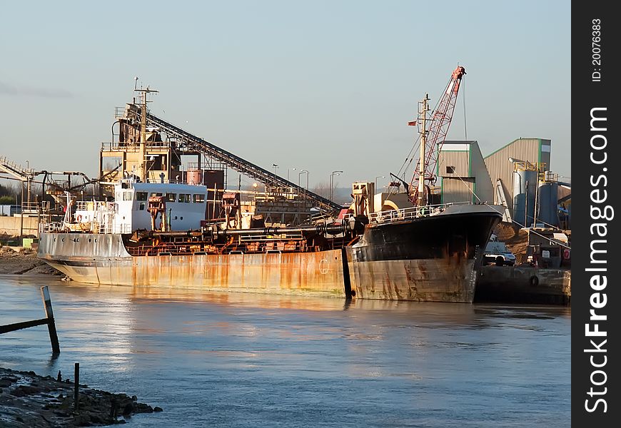 A dredger ship delivers gravel at a port on a winter afternoon. A dredger ship delivers gravel at a port on a winter afternoon.