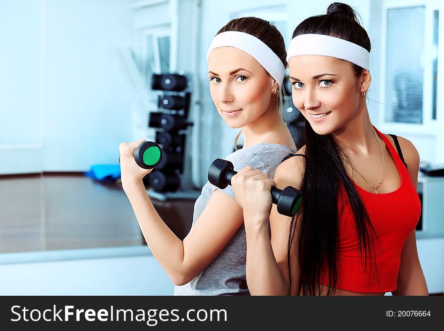 Two young sporty women in the gym centre.
