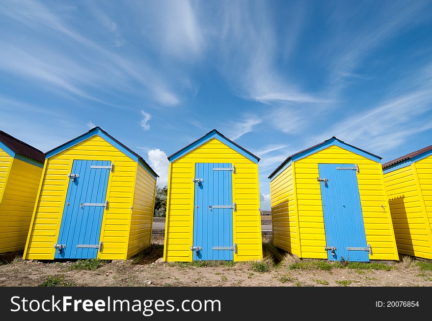 Wide angle view of bright beach huts with exagerated verticals on a beach in England. Wide angle view of bright beach huts with exagerated verticals on a beach in England