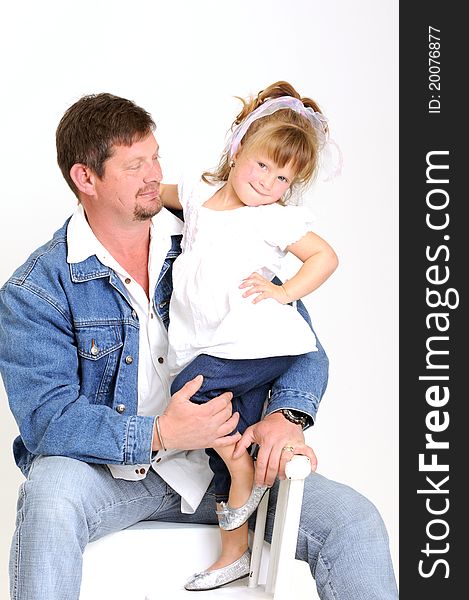 Young father dressed in jeans and toddler girl dressed in white hugging and smiling lovingly. Young father dressed in jeans and toddler girl dressed in white hugging and smiling lovingly