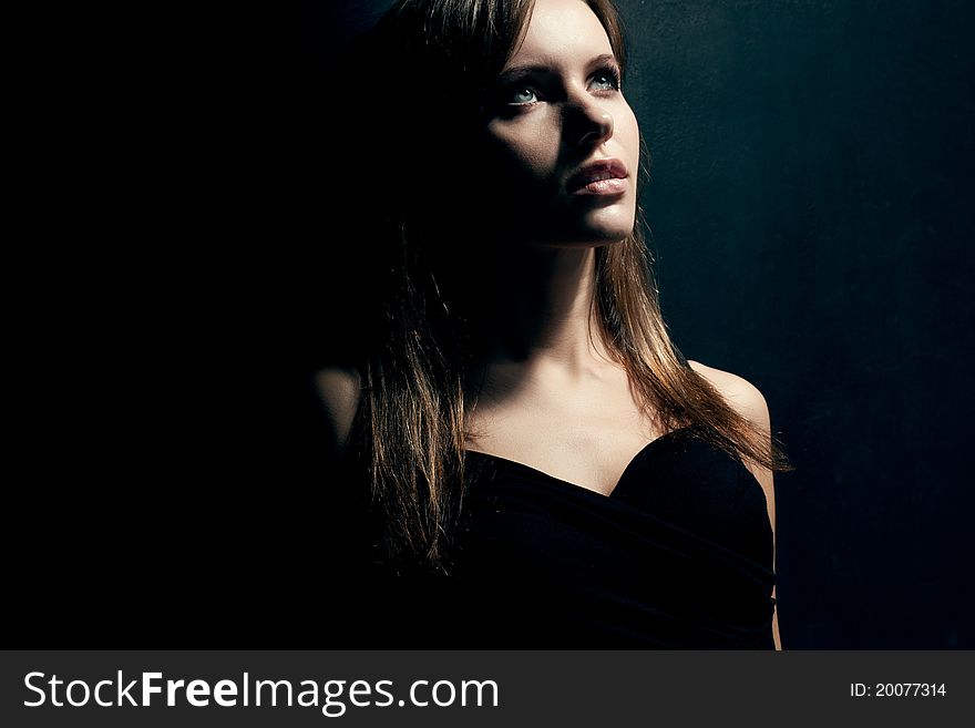 Beautiful woman portrait wearing black dress over dark background. Beautiful woman portrait wearing black dress over dark background