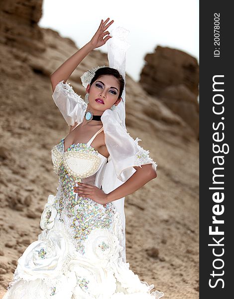 Beautiful Asian wearing a white gown posing outside holding a veil. Beautiful Asian wearing a white gown posing outside holding a veil