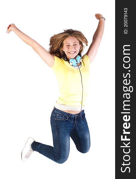 Girl jumping high with headphones around her neck, indoors.