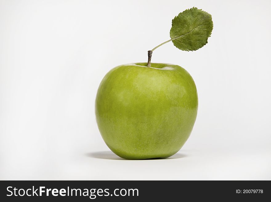 Fresh green apple with single leaf on isolated white background