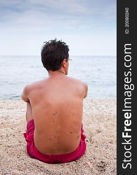 Young Man Sitting Alone On The Beach