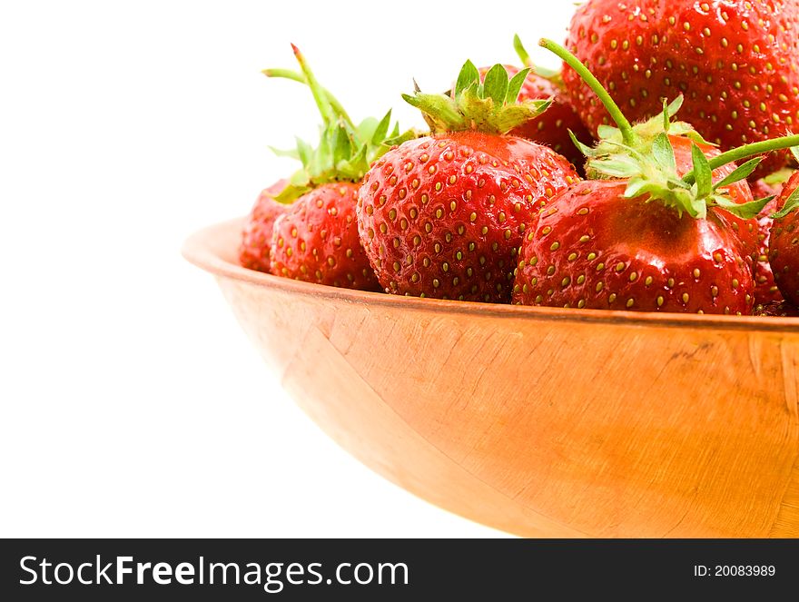 The red ripened strawberry lying in a wooden bowl (isolated). The red ripened strawberry lying in a wooden bowl (isolated)