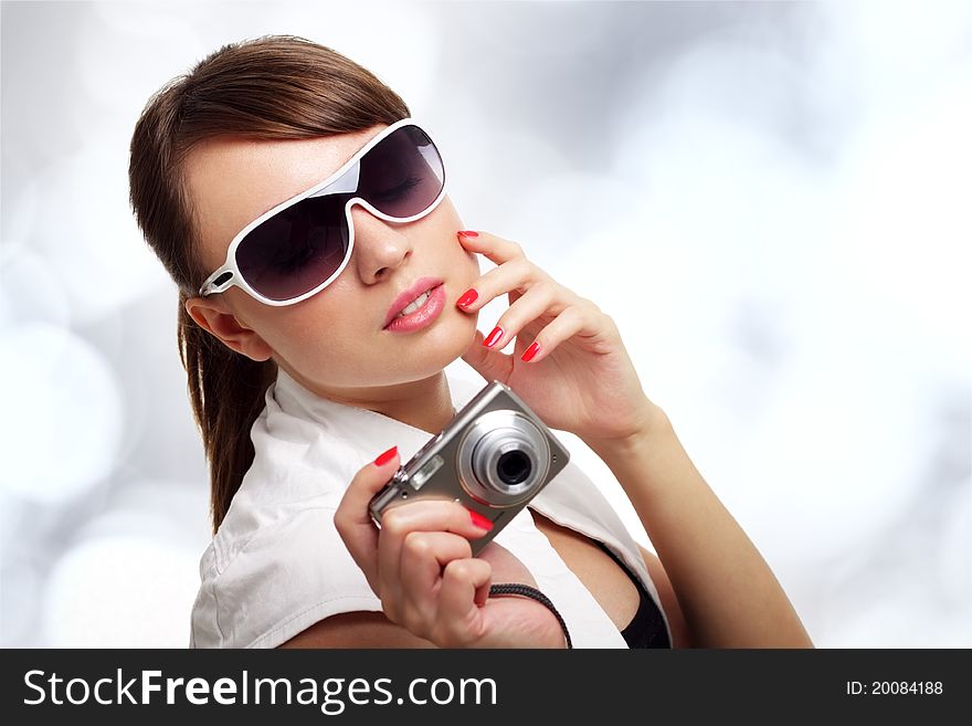 Young stylish woman with a camera on a light background