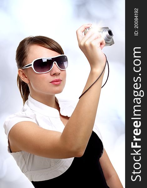 Young stylish woman with a camera on a light background