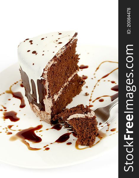 Chocolate cake with chocolate sauce and a fork on a white plate. Chocolate cake with chocolate sauce and a fork on a white plate