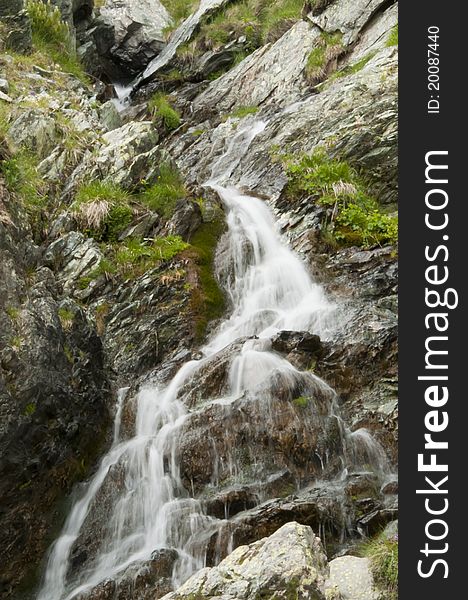 Beautiful mountain waterfall over mossy rocks