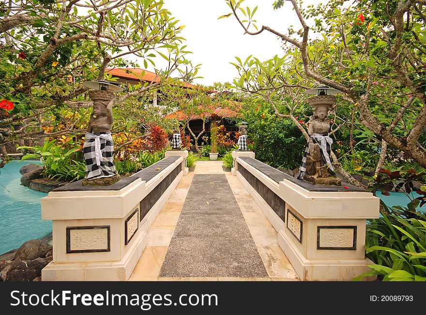 Bridge with traditional statues in beautiful garden on luxury tropical resort. Bali, Indonesia. Bridge with traditional statues in beautiful garden on luxury tropical resort. Bali, Indonesia.