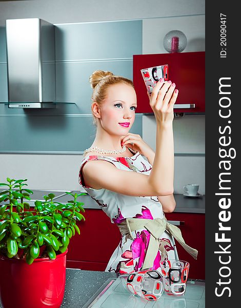 Housewife with clean glass in interior of kitchen