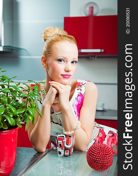 Blond Girl With Glass In Interior Of Kitchen