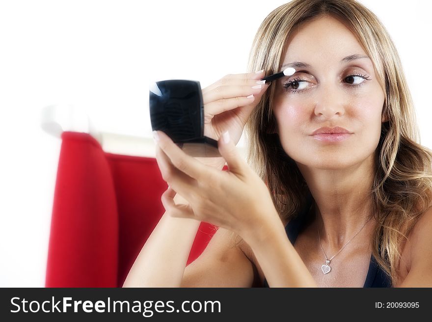 Blond woman applying eye shadow to her eyes. Blond woman applying eye shadow to her eyes