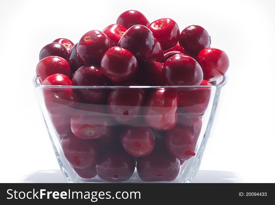 A pile of fresh large cherries in a small bowl on a white background. A pile of fresh large cherries in a small bowl on a white background
