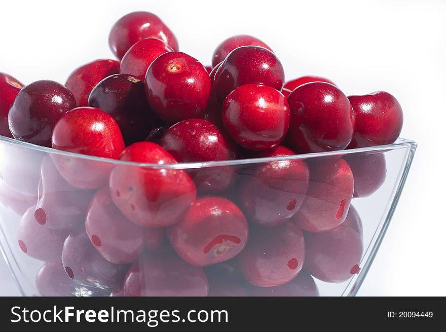 A pile of fresh large cherries in a small bowl on a white background. A pile of fresh large cherries in a small bowl on a white background