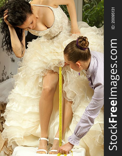 Women making adjustment to wedding gown in professional fashion designer studio. Women making adjustment to wedding gown in professional fashion designer studio