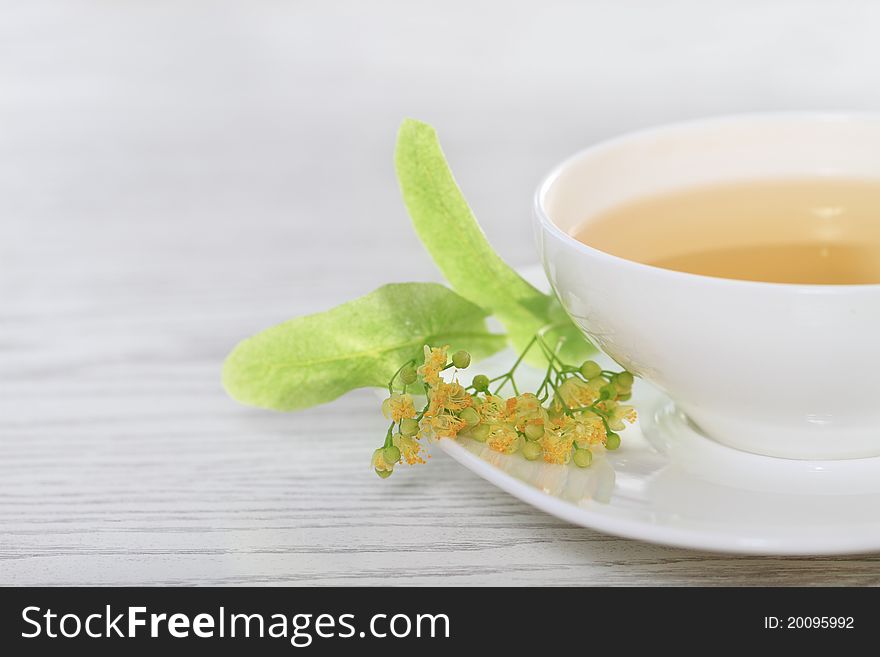 Cup of the linden tea on white wooden background. Cup of the linden tea on white wooden background