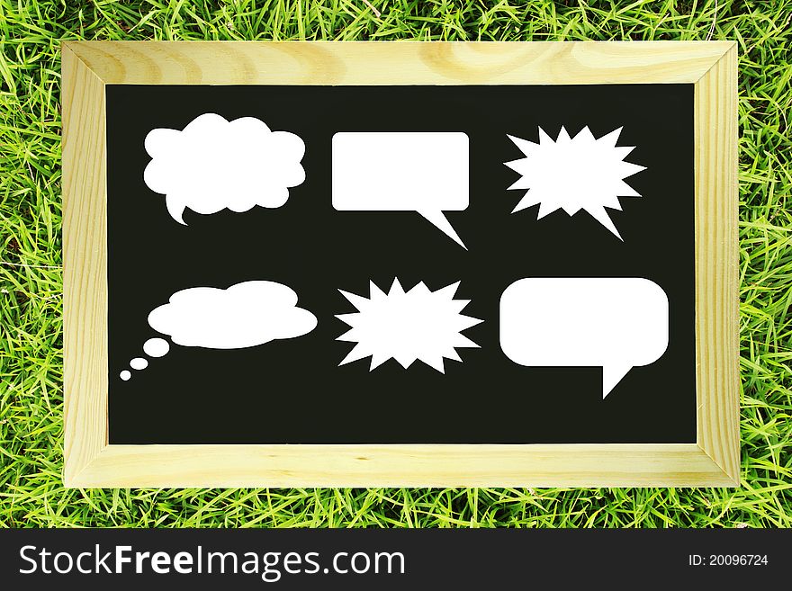 Speech balloon blank message on blackboard on green grass. Speech balloon blank message on blackboard on green grass