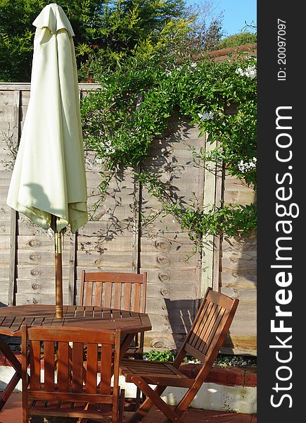 Wooden table and chairs with parasol on patio in garden. Wooden table and chairs with parasol on patio in garden