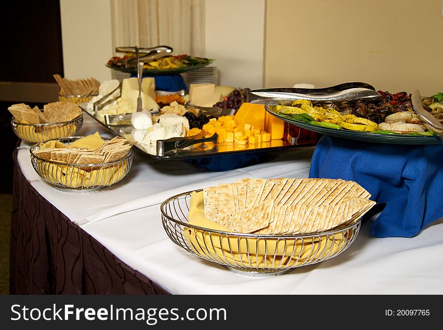 A buffet table is set out with various cheese and cracker selections at event. A buffet table is set out with various cheese and cracker selections at event.