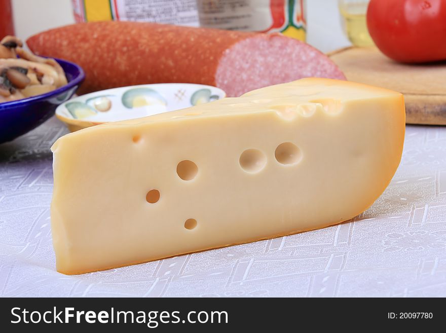 Slab of cheese with big round holes over background of other defocused ingredients for pizza. Slab of cheese with big round holes over background of other defocused ingredients for pizza