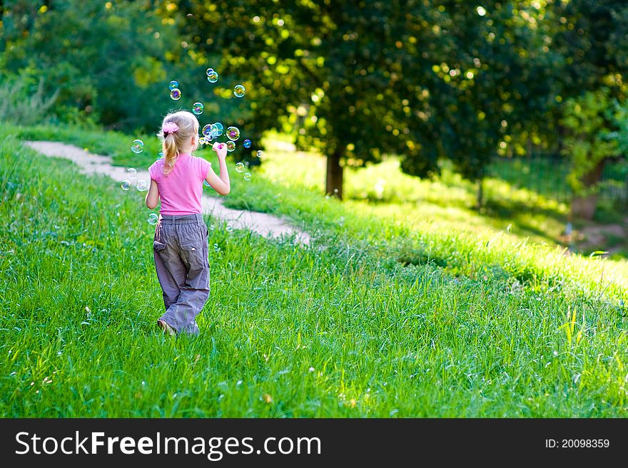 Little girl on green grass blow bubbles. Little girl on green grass blow bubbles