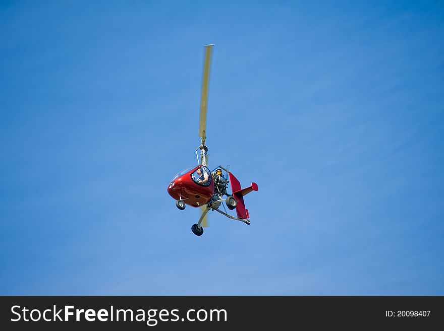 In the blue sky flying a small helicopter crimson