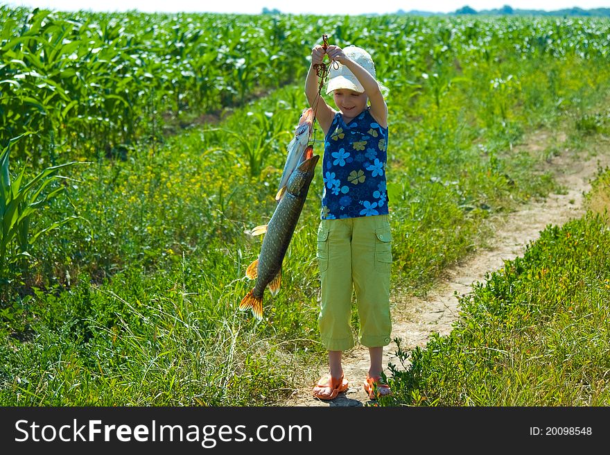 The little girl holds a catch - a big pike. The little girl holds a catch - a big pike