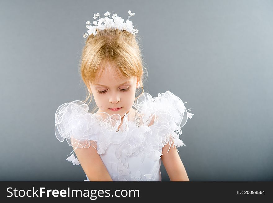 The little girl in a white party dress is preparing for the holiday. The little girl in a white party dress is preparing for the holiday