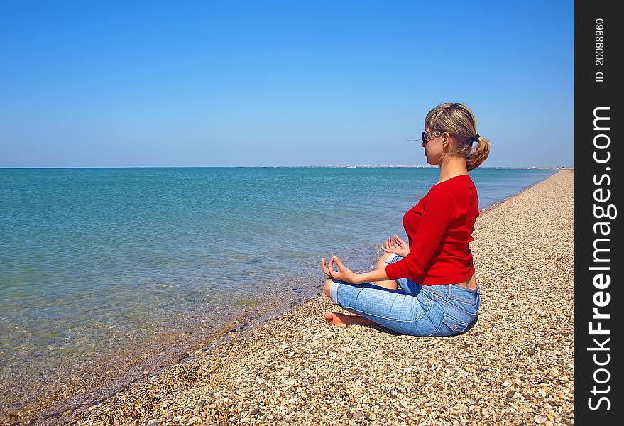 Girl in yoga position sitting on an empty beach near the sea. Girl in yoga position sitting on an empty beach near the sea