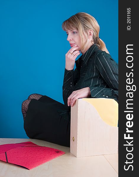 A thinking woman sorting through folders whilst sitting on a table