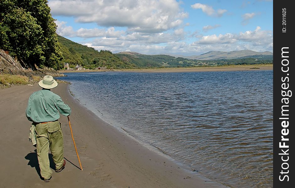 Image of a man walking along a deserted beach in wales. Image of a man walking along a deserted beach in wales