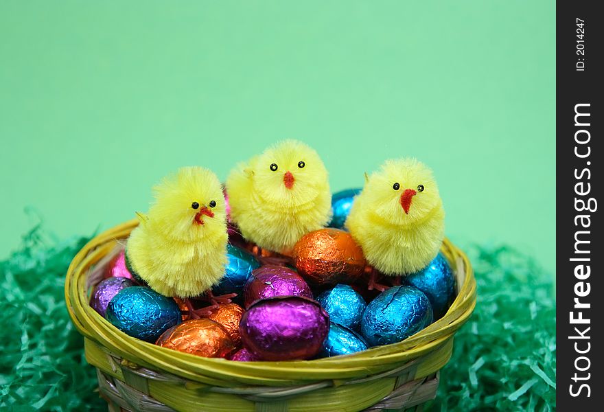 Coloured sweet  easter eggs and three chicken in grass  on green background