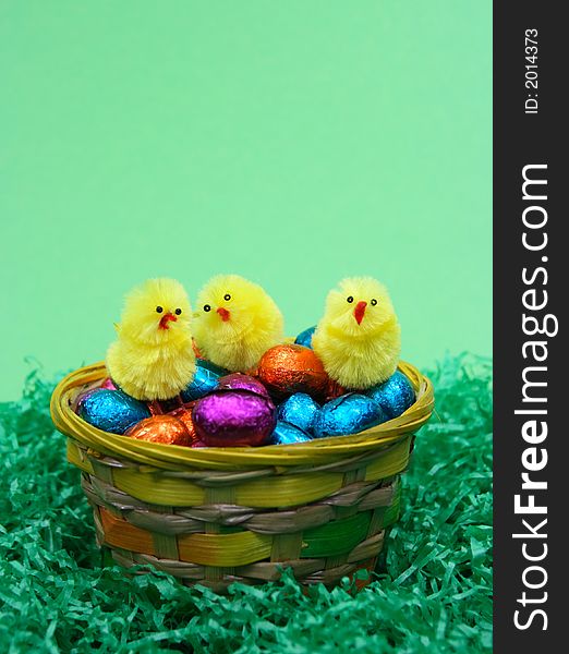 Coloured sweet  easter eggs and three chicken   on green background