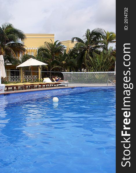 Swimming pool with beach chairs and part of a hotel with hacienda like details in Cancun, Riviera Maya, Quinatan Roo, Mexico, Latin America. Swimming pool with beach chairs and part of a hotel with hacienda like details in Cancun, Riviera Maya, Quinatan Roo, Mexico, Latin America