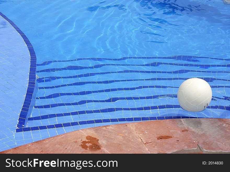 White volleyball floating in the water of a swimming pool. White volleyball floating in the water of a swimming pool