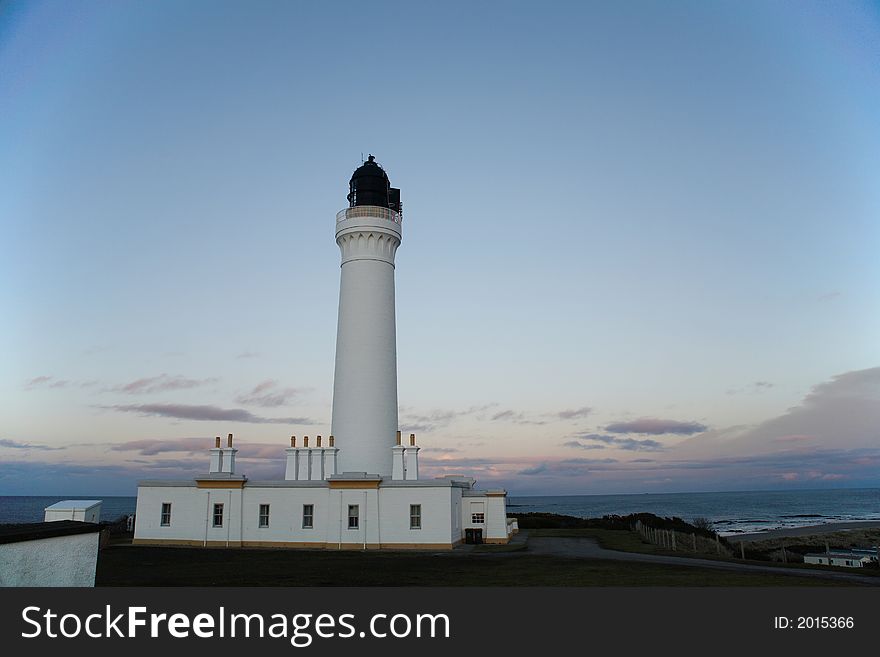 A white lighthouse with the sea in the background.