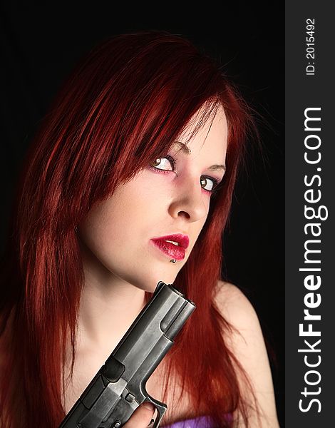 Closeup of a young redhead woman holding a gun. Closeup of a young redhead woman holding a gun