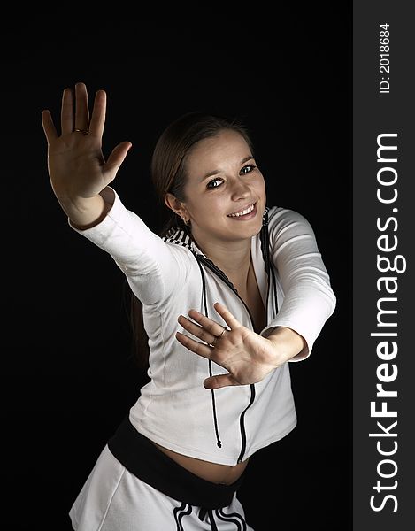 Girl with raised hands in white sportive wear on black background. Girl with raised hands in white sportive wear on black background