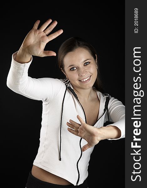 Smiling girl with raised hands in white sportive wear on black background. Smiling girl with raised hands in white sportive wear on black background