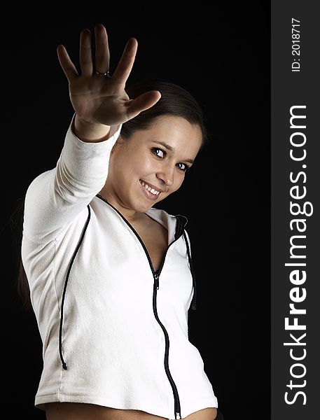 Smiling girl with raised hand in white sportive wear on black background. Smiling girl with raised hand in white sportive wear on black background