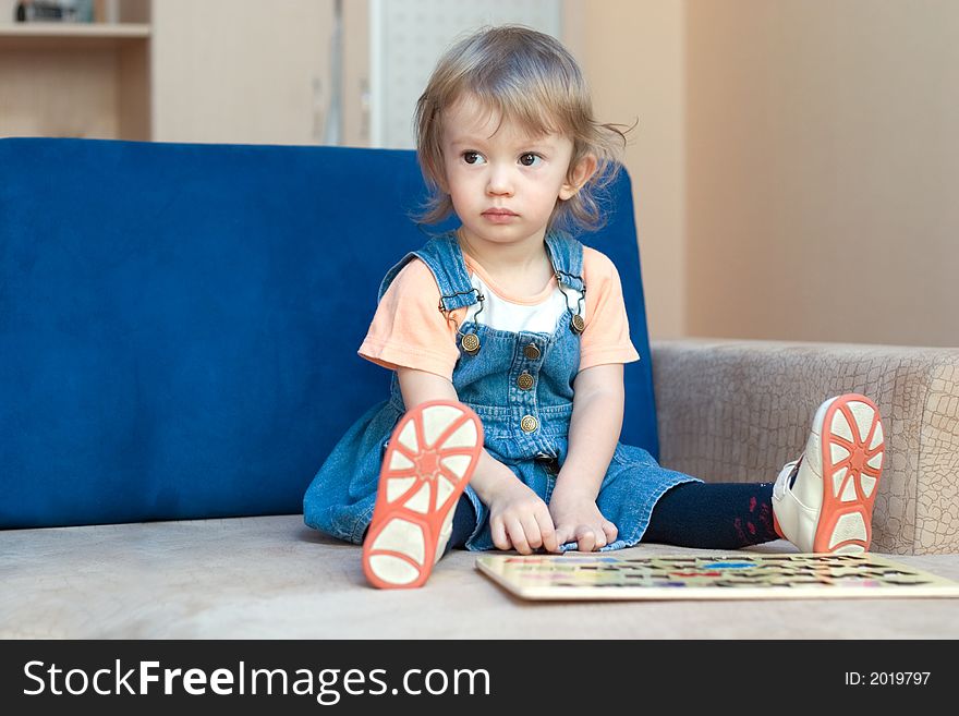 Little cute girl sitting on the sofa. With copy space