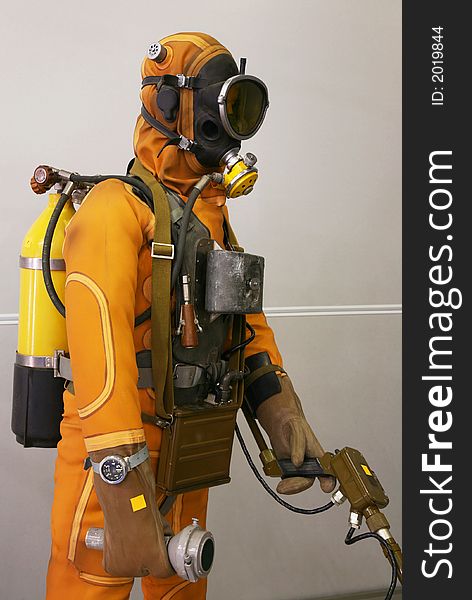 The mannequin is dressed in a orange diving suit with a cargo, hoses and oxygen cylinders