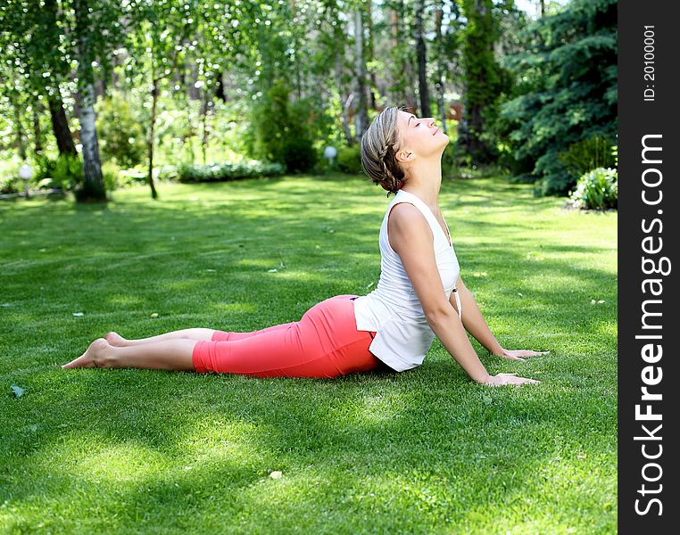 Young girl in a white shirt and red pants doing yoga outdoors