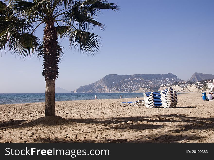 Beach with stacked sunbeds in Alicante, Spain