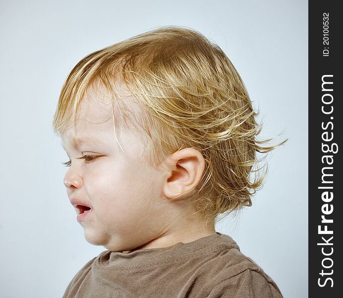 Colorful Closeup studio portrait of a crying handsome one year old blonde boy, shot against blue background. Colorful Closeup studio portrait of a crying handsome one year old blonde boy, shot against blue background.