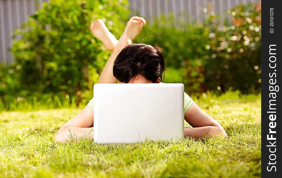 Caucasian woman is lying on the grass with laptop. Caucasian woman is lying on the grass with laptop