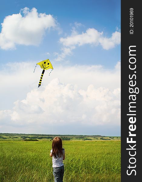Little girl with flying a kite in the summer field