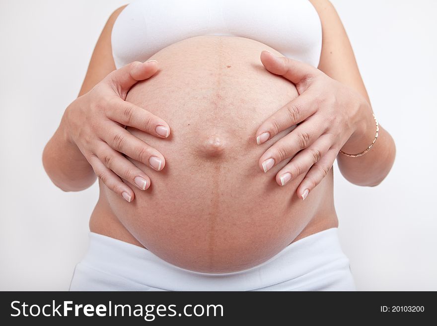 Pregnant woman hold hands on a belly isolated